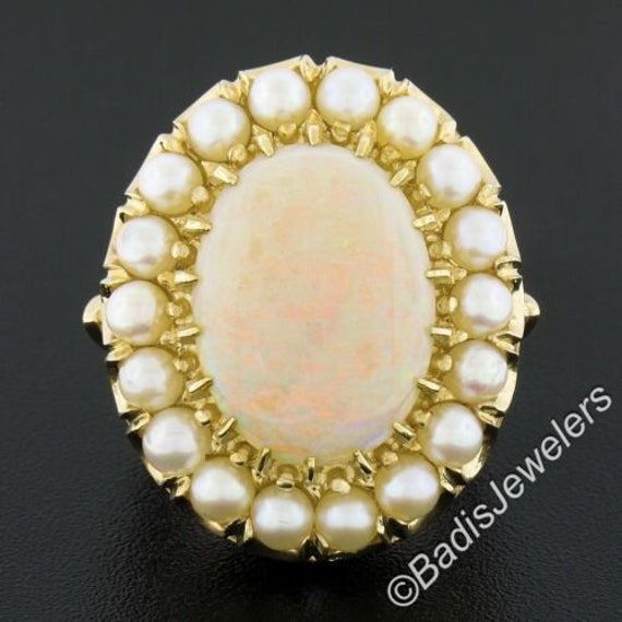 This gorgeous well made vintage ring is crafted in solid 14k yellow gold and features a stunning oval cabochon opal stone having a white base color and displays a light green and orange play throughout. The center stone is surrounded by a halo of 18 round ball shaped cultured pearls. This vintage ring is in excellent condition, and ready to make a statement! Enjoy :) --Stone(s):-- (1) Natural Genuine Opal - Oval Cabochon Cut - Multi Prong Set - White Base w/ Light Green and Orange Play - 16.3x12 Luxury Oval Cabochon Pearl Ring, Luxury Hallmarked Oval Cabochon Opal Ring, Classic Oval Opal Ring Collectible, Oval Cabochon Opal Ring Fine Jewelry, Oval Cabochon Opal Ring In Fine Jewelry, Fine Jewelry Oval Cabochon Opal Ring, Heirloom Oval Cabochon Opal Ring, Heirloom Oval Opal Ring Collectible, Heirloom White Opal Ring Oval Cabochon