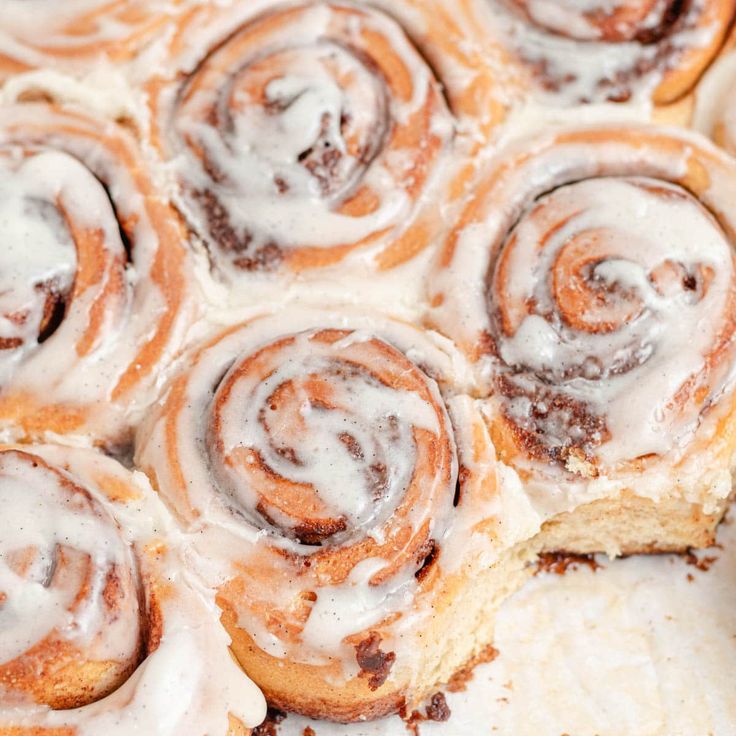 cinnamon rolls with icing sitting on top of each other