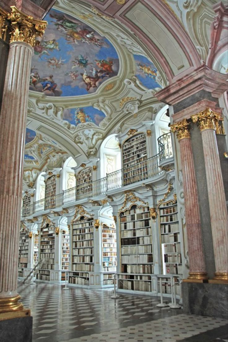 the interior of an old library with columns and paintings on the walls, along with marble flooring