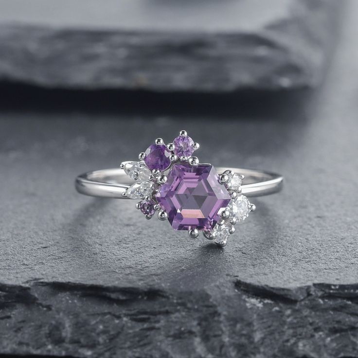 an amethorate and diamond ring sitting on top of a rock