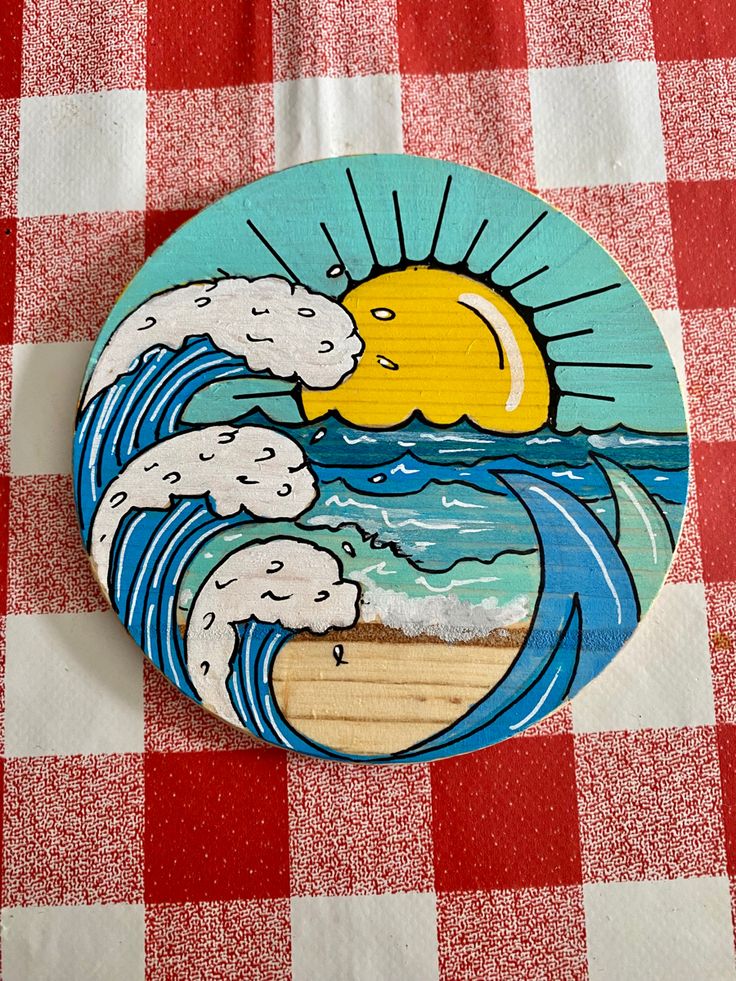 a wooden plate with an image of the sun and waves on it sitting on a checkered tablecloth