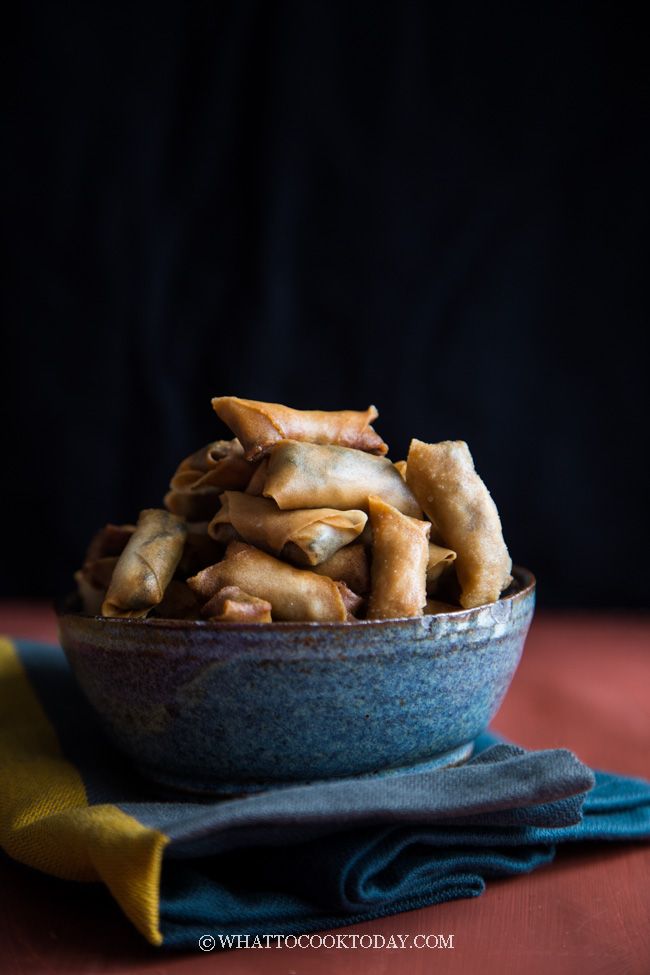 a blue bowl filled with fried food on top of a red table cloth next to a yellow napkin