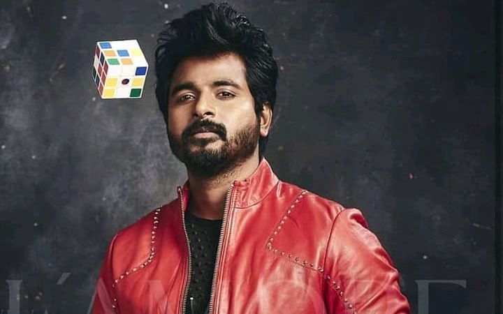 a man wearing a red leather jacket with a rubik cube on his head in front of him