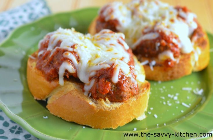 two stuffed meatball sandwiches on a green plate