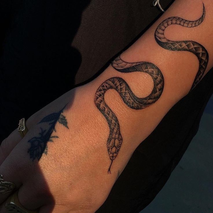 a person's arm with a snake tattoo on it