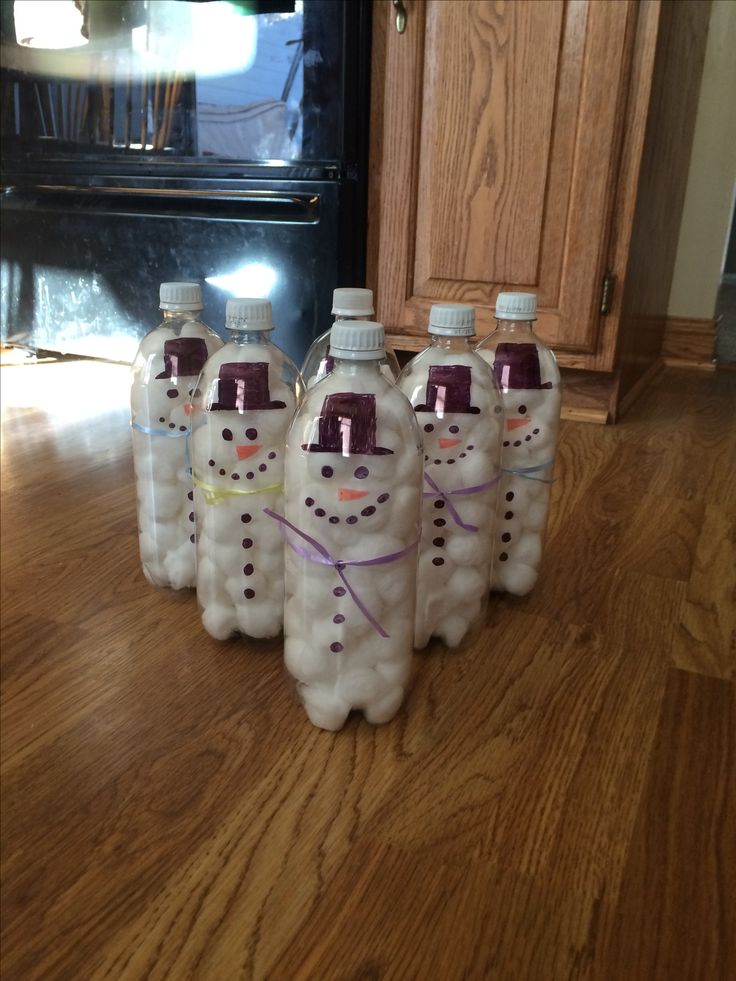 four plastic bottles with snowmen on them sitting on the floor in front of an oven