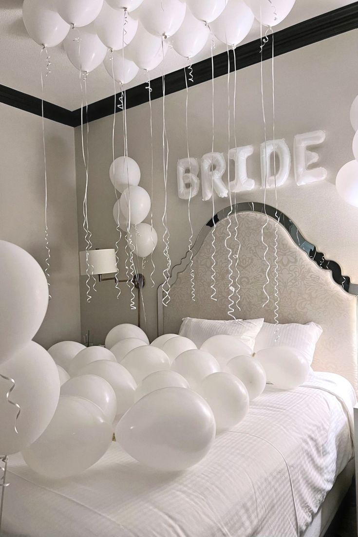 white balloons are floating in the air above a bed