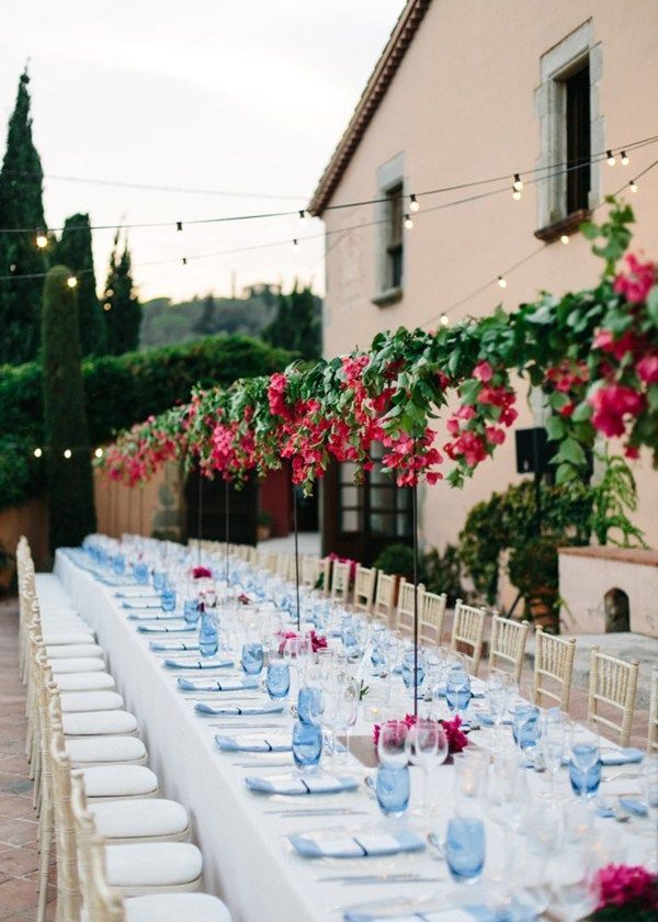 a long table is set with blue and white plates, silverware and pink flowers