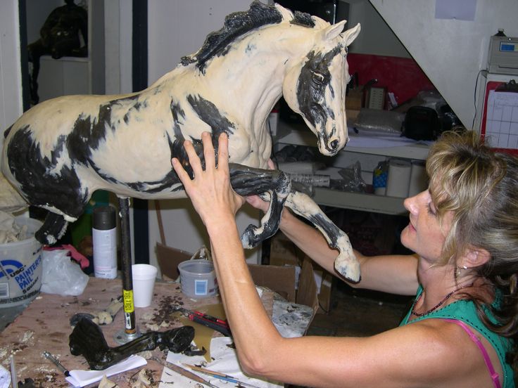 a woman working on a statue of a horse