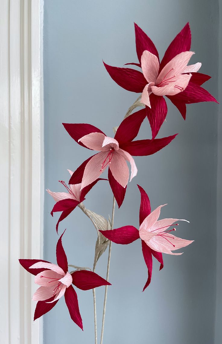 three pink flowers in a vase on a table