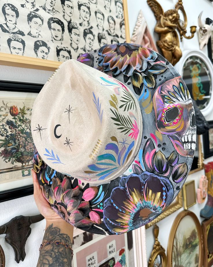 a person holding up a hat in front of a wall with pictures and clocks on it