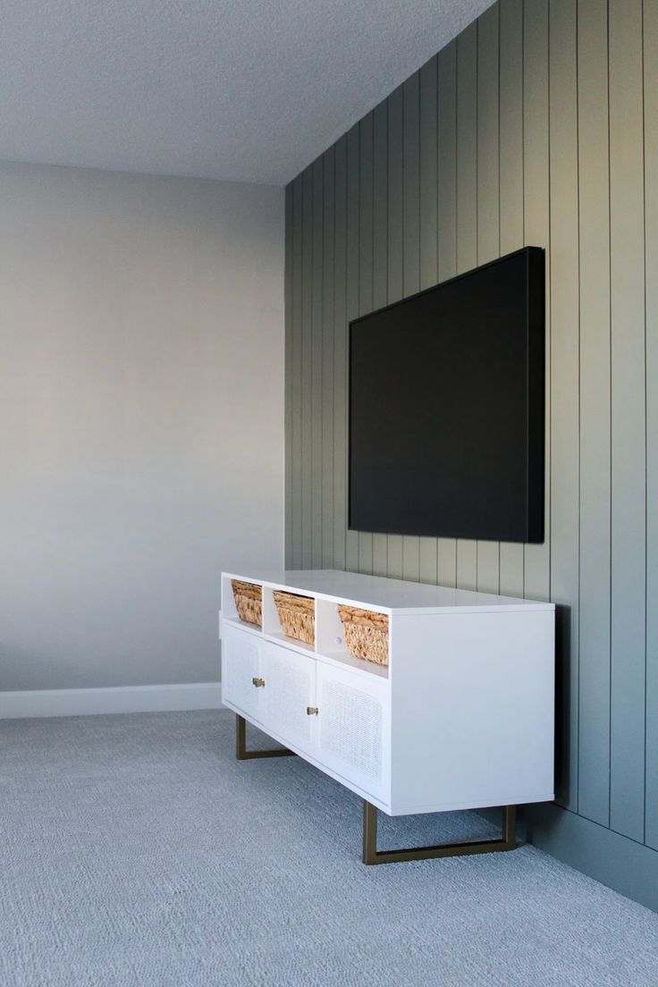 a flat screen tv mounted to the side of a white cabinet in a living room