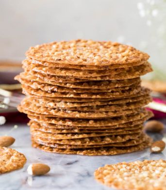 a stack of cookies sitting on top of a table next to some nuts and flowers