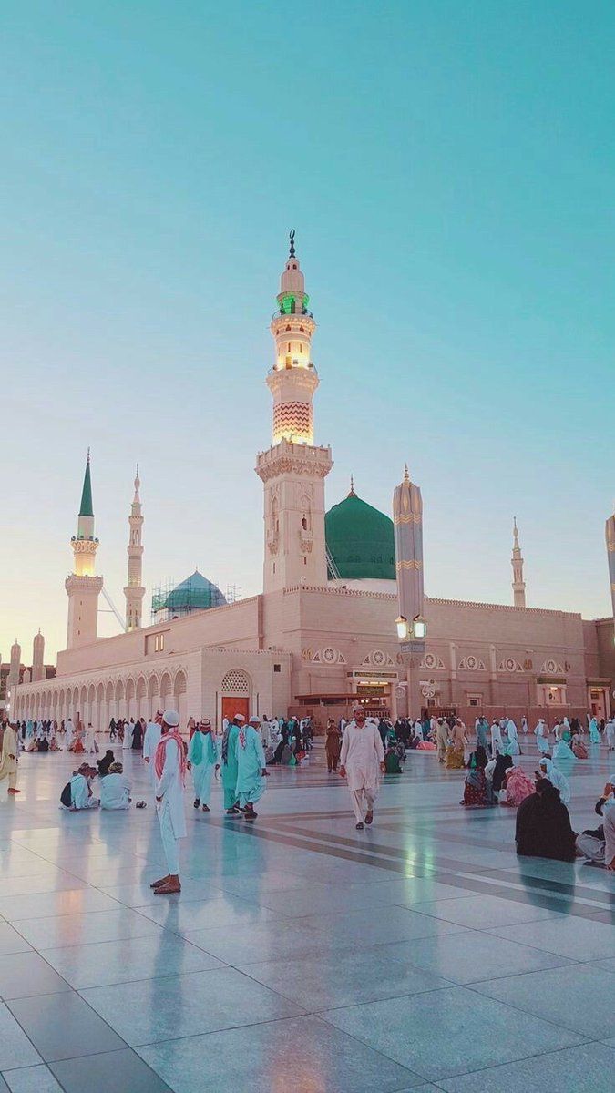 many people are sitting on the ground in front of a large building with green domes