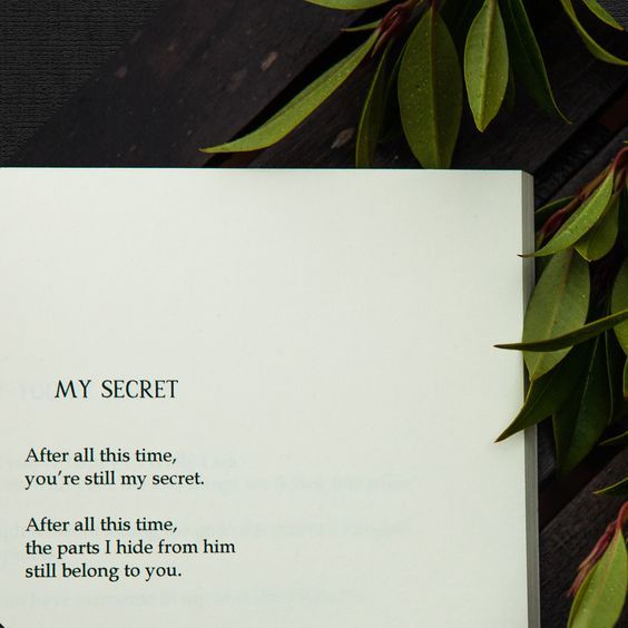 an open book sitting on top of a wooden table next to green leafy plants