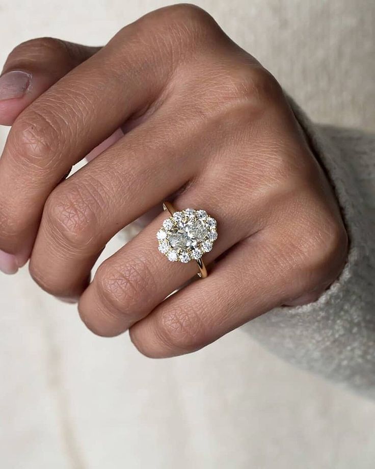 a woman's hand with a diamond ring on top of her finger and the other hand holding an engagement ring