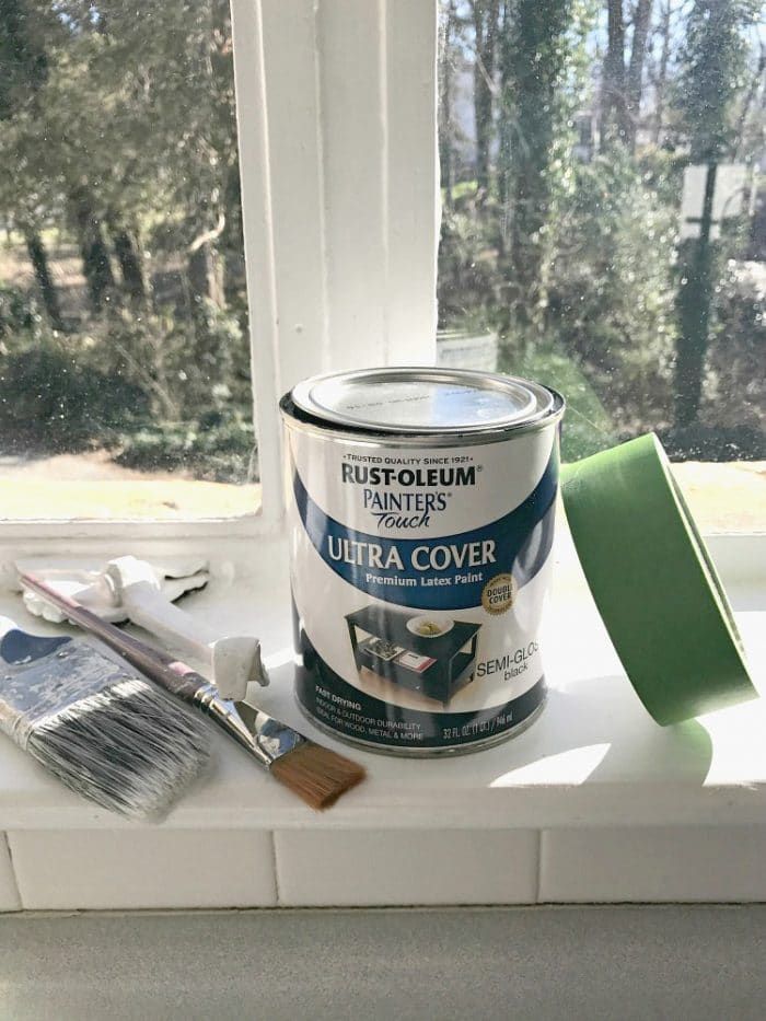 a can of paint sitting on top of a window sill next to a brush