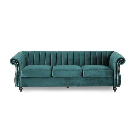 a green velvet couch with wooden legs and nail polishing on the armrests