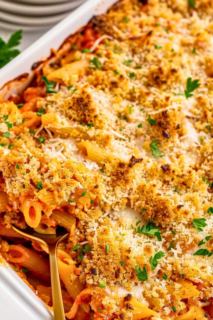 a casserole dish with pasta and parmesan cheese on top, garnished with parsley