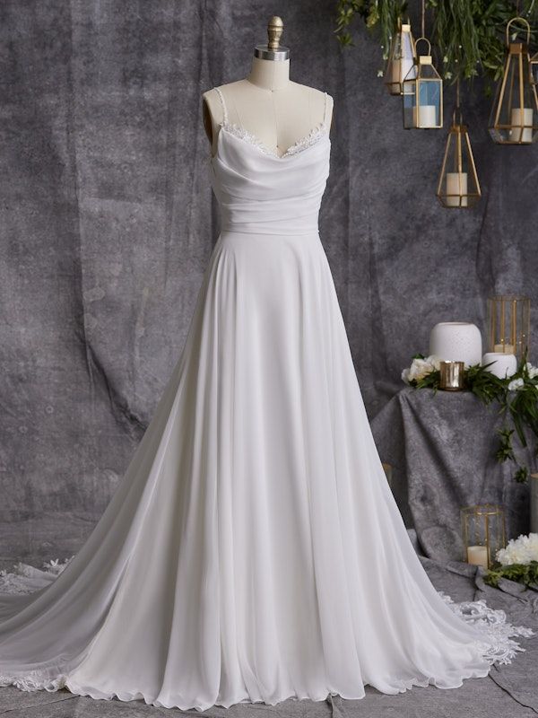 a white wedding dress on a mannequin in front of a backdrop with flowers