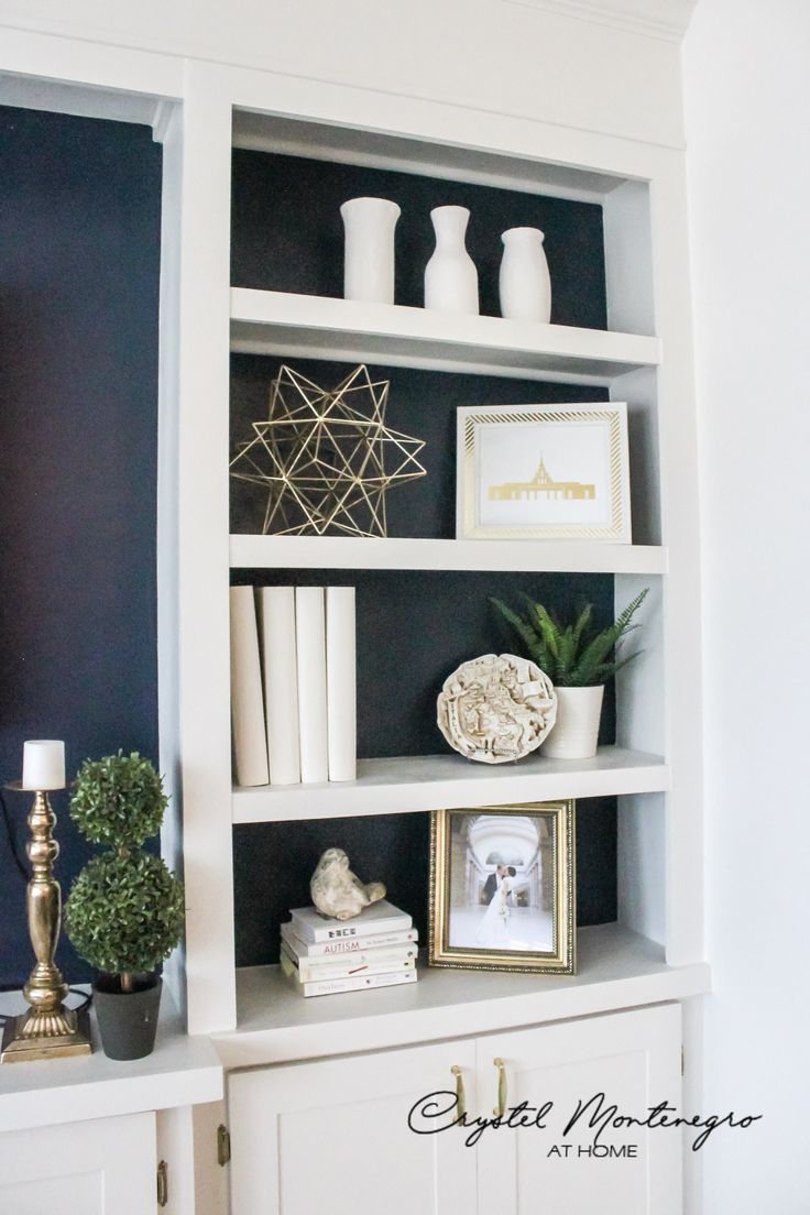 a white bookcase filled with books and pictures