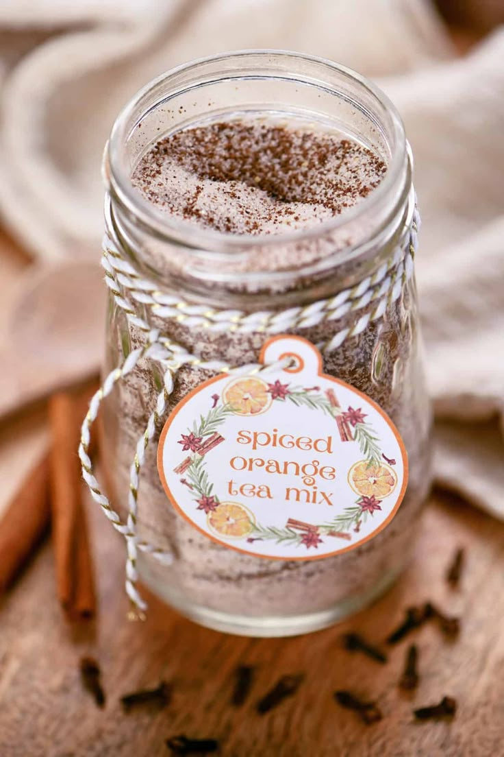 spiced orange tea mix in a glass jar on a wooden table with cinnamon sticks