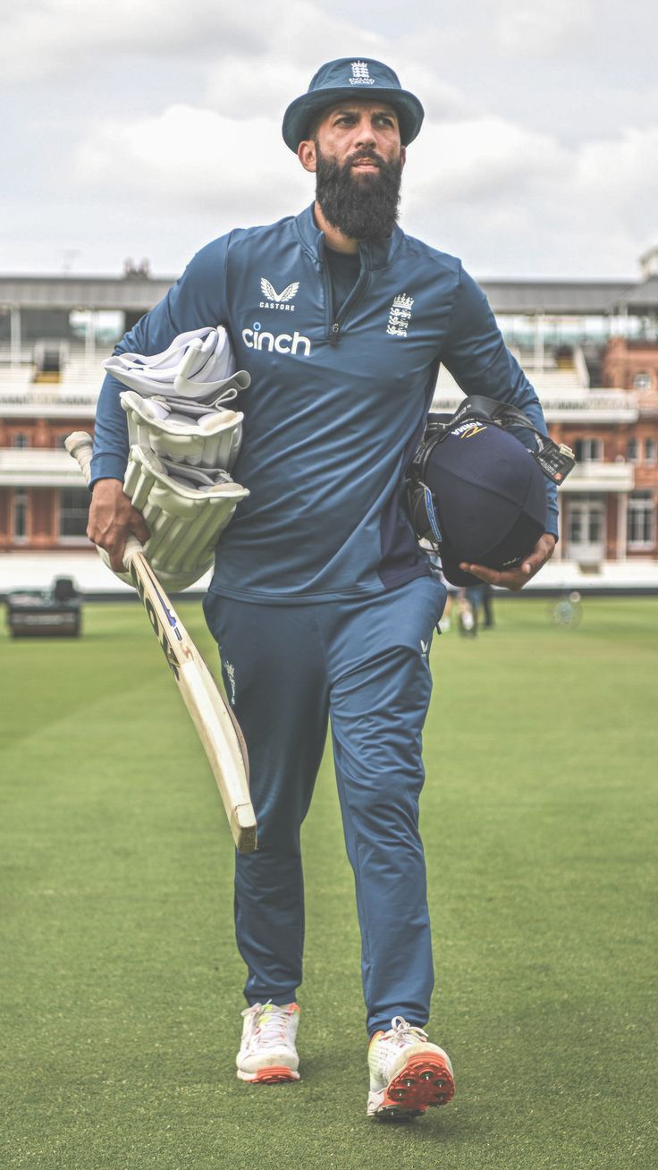 a man walking across a field holding a cricket bat and ball in his hand,