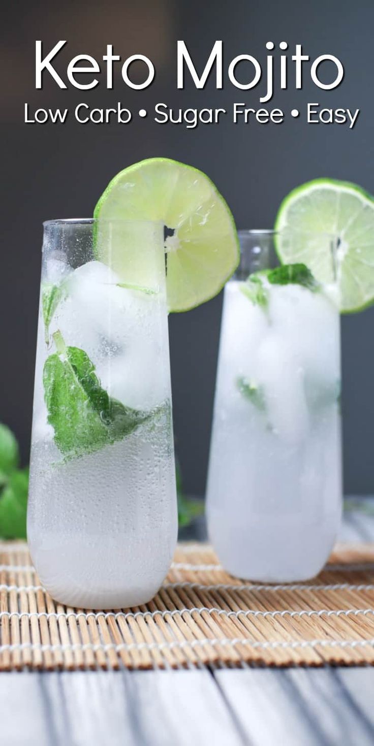 two glasses filled with ice and limes on top of a wooden table next to mint leaves