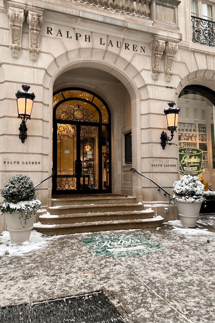 an entrance to a building with snow on the ground and potted plants in front