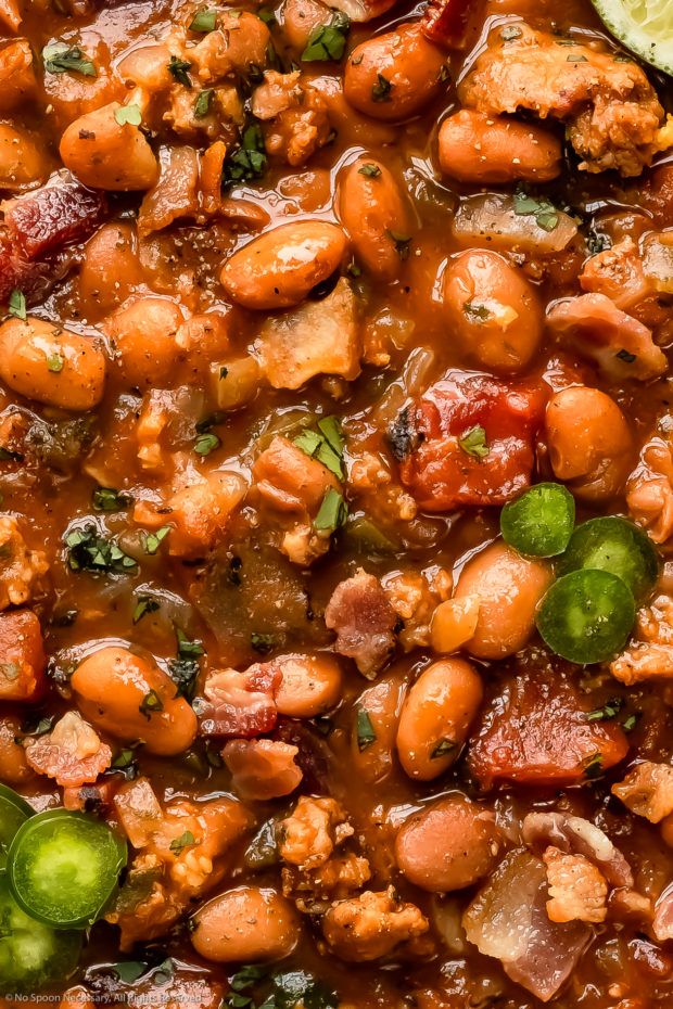 a bowl filled with beans and meat next to a lime slice on top of a table