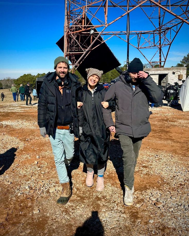 three people are standing in front of a structure