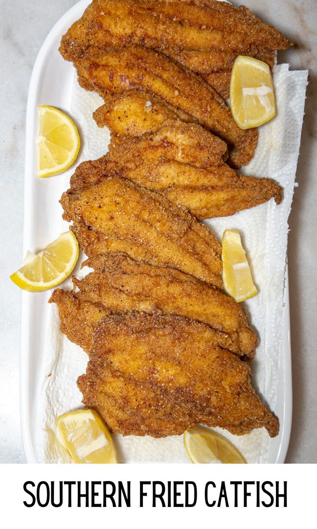 fried fish on a plate with lemon wedges