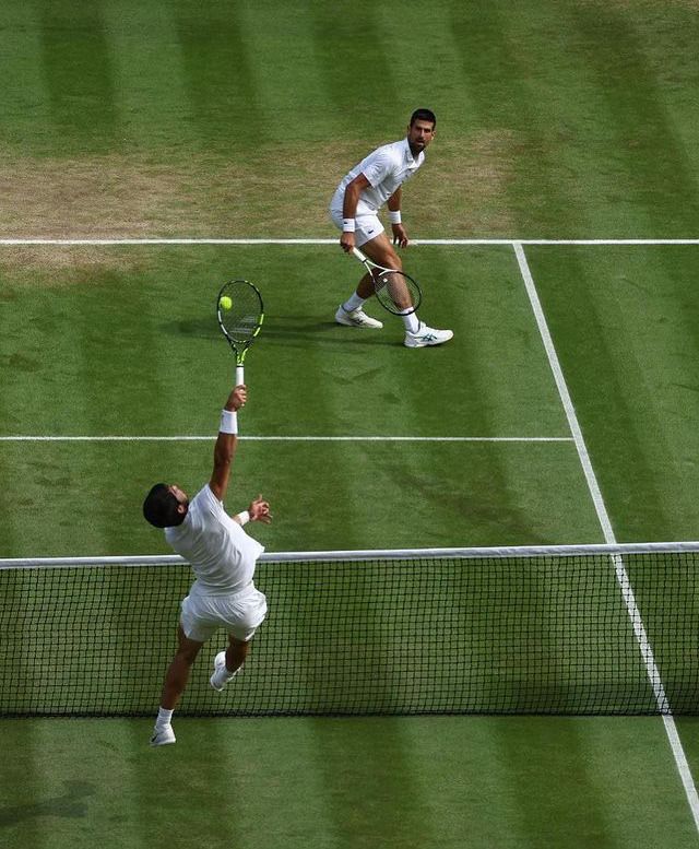 two men playing tennis on a grass court