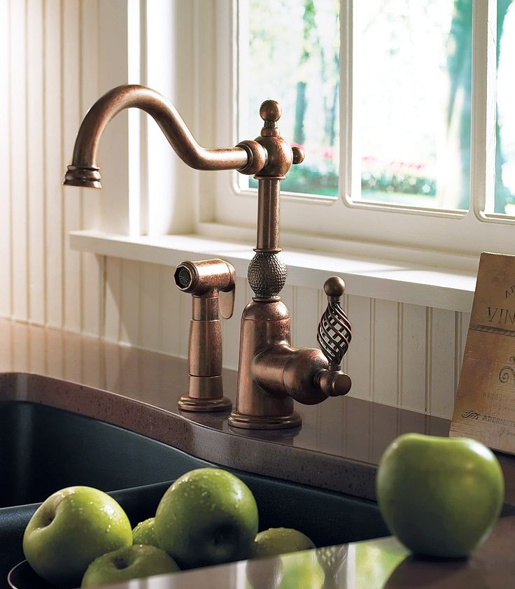 an old fashioned kitchen faucet with green apples on the counter