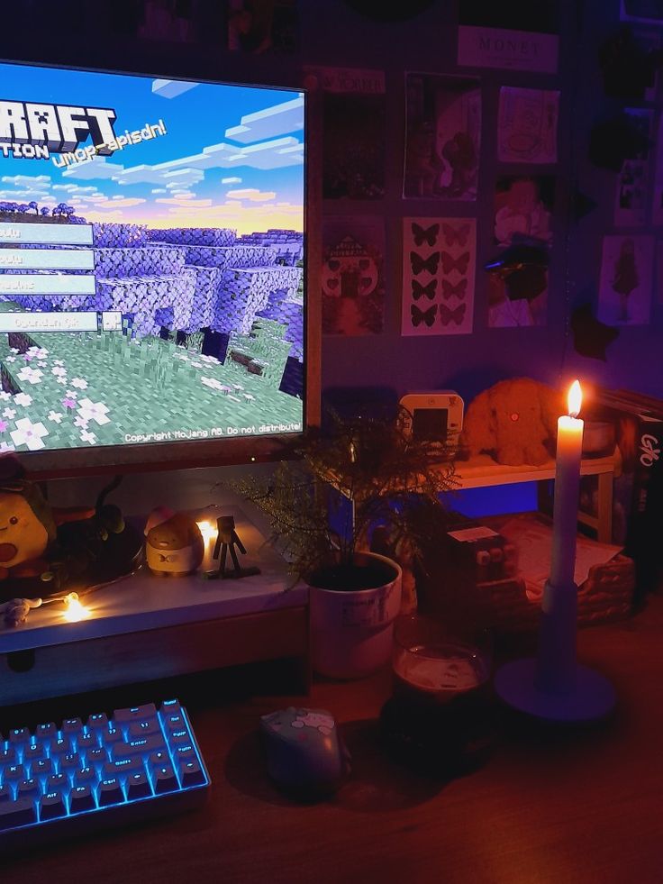 a desk with a computer monitor, keyboard and candles on it in front of a purple background