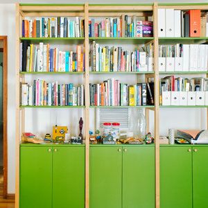 a green bookcase filled with lots of books on top of a hard wood floor