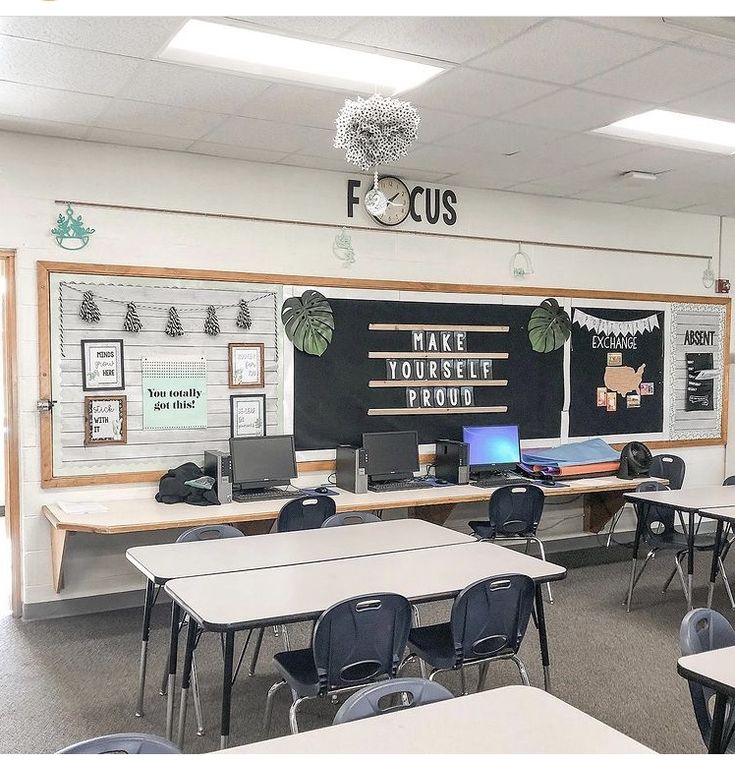 an empty classroom with desks and laptops on the tables in front of it