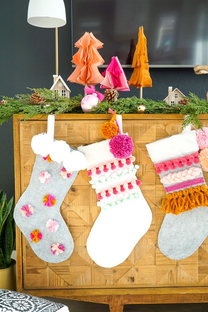 three christmas stockings hanging on a wooden cabinet