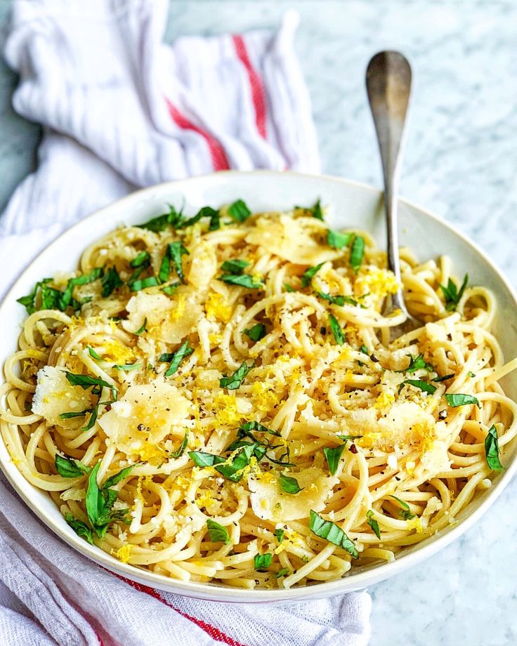 a white bowl filled with pasta and topped with parsley