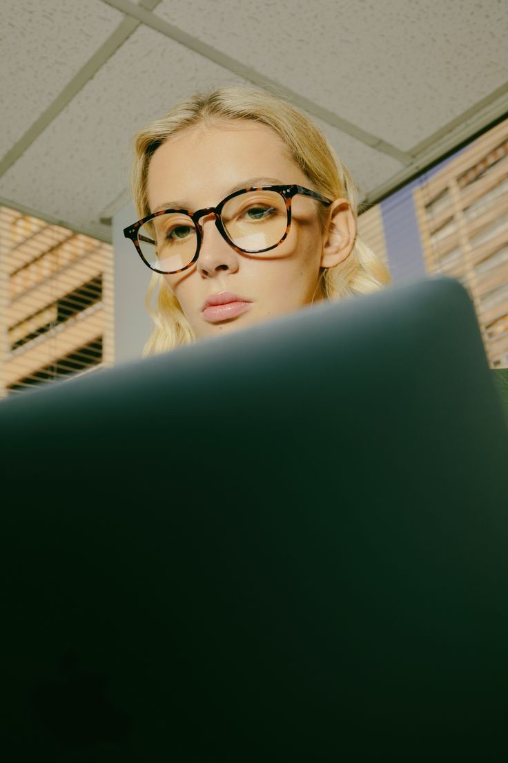 a woman wearing glasses looking at a computer screen