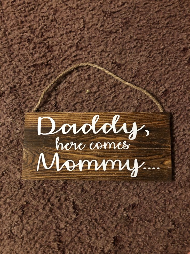 a wooden sign that says daddy, here comes mommy hanging on the wall in front of a carpeted area