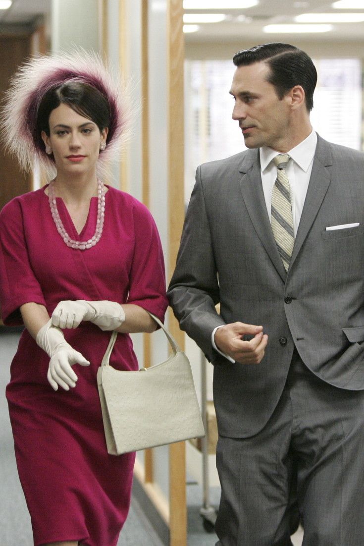 a man in a suit and tie walking next to a woman in a red dress