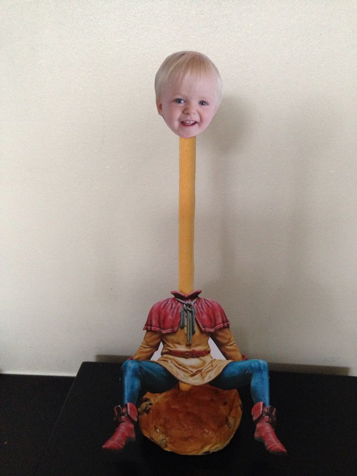 a little boy sitting on top of a piece of bread with a pencil sticking out of it