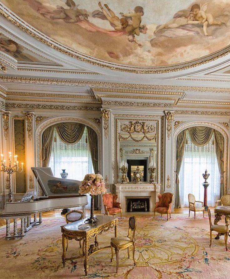 an ornate living room with chandeliers and paintings on the ceiling, painted in gold