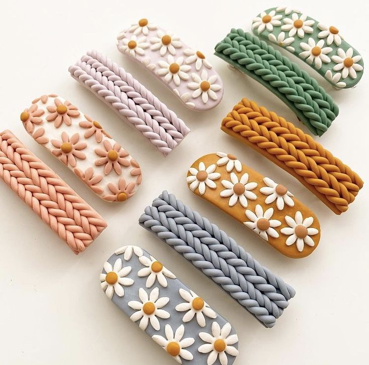 six different colored hair clips with daisies on the ends and braiding around them