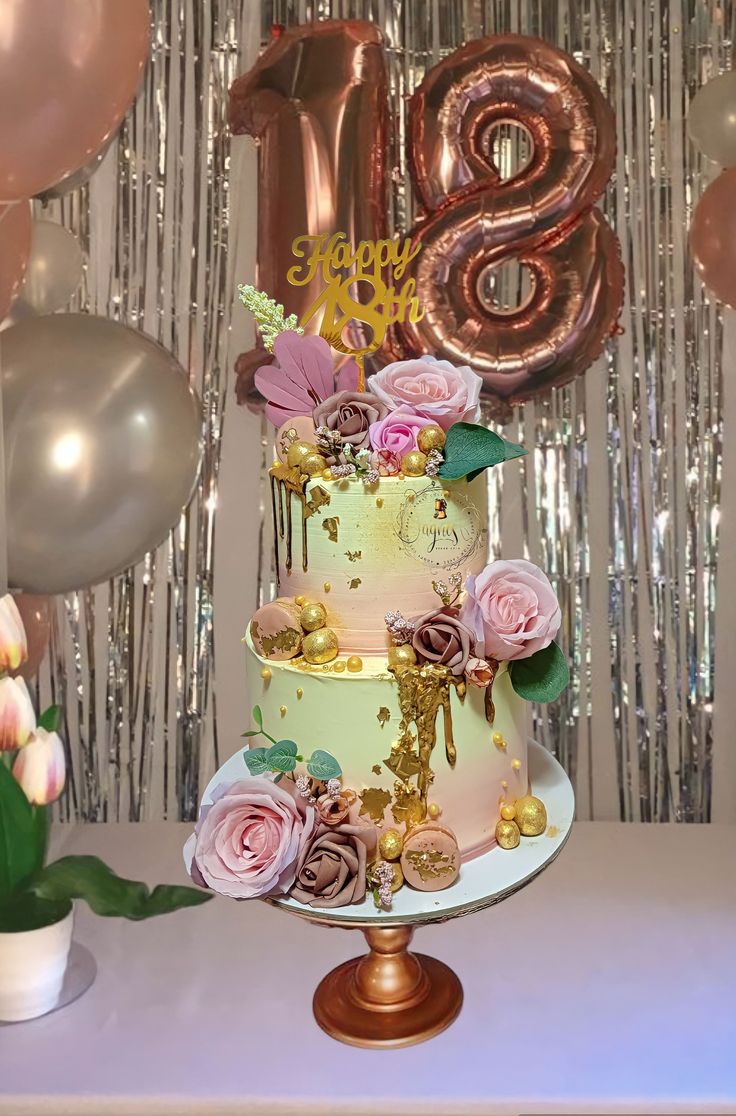 a three tiered cake sitting on top of a table next to balloons and flowers