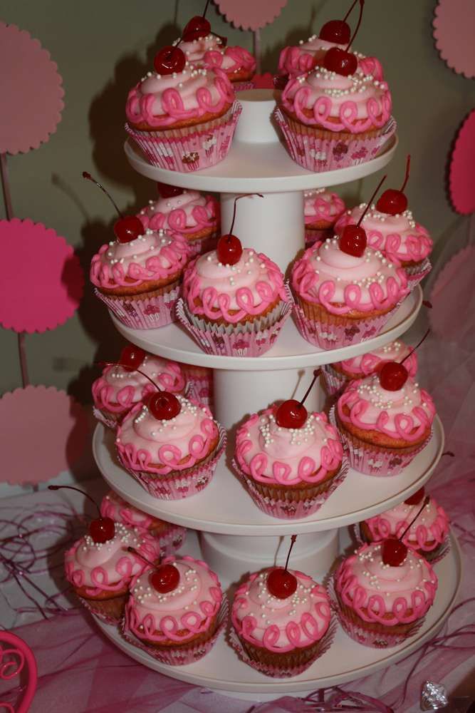 there are cupcakes on the three tiered cake stand with cherries in them