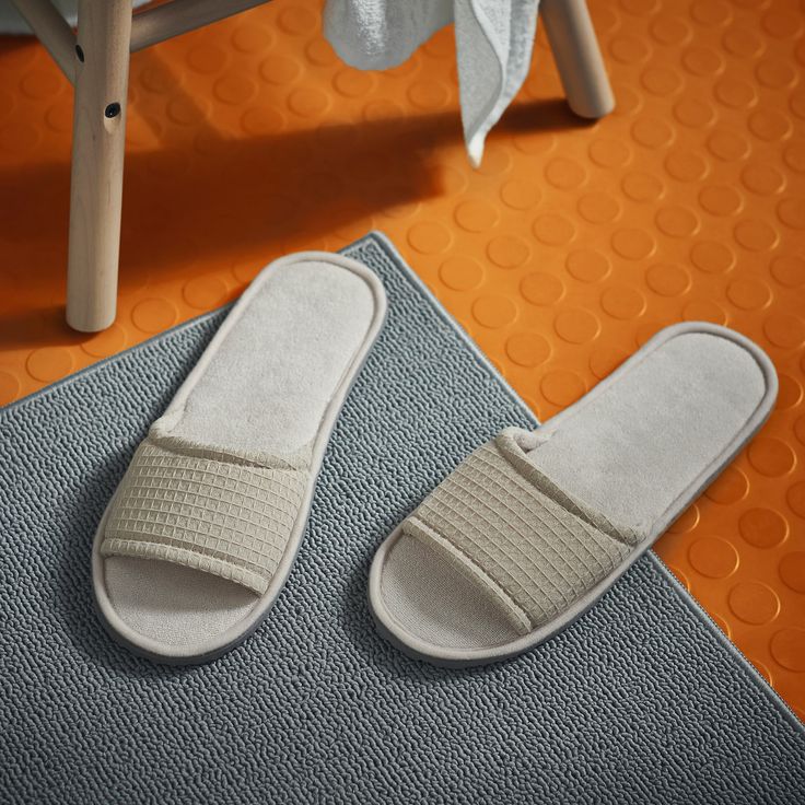 a pair of white slippers sitting on top of a rug next to a chair