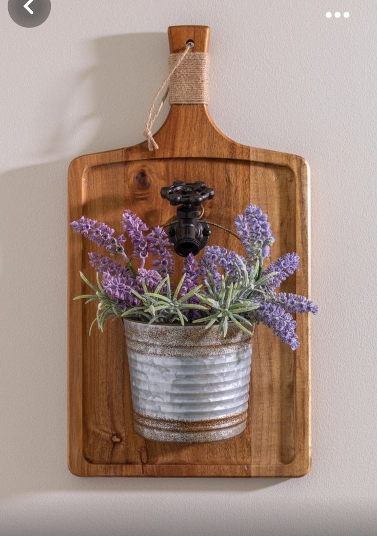 a metal bucket with flowers in it hanging on a wall next to a wooden plaque