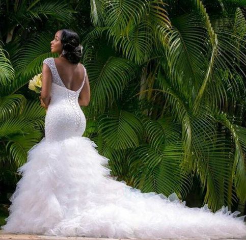 a woman in a wedding dress standing next to palm trees